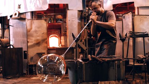 Caucasian glassblower free blowing glass at glassblowing factory 4k