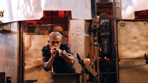 Glassblower free blowing glass at glassblowing factory 4k