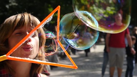 Woman blow a beautiful colored soap bubbles outdoors in public park slow motion