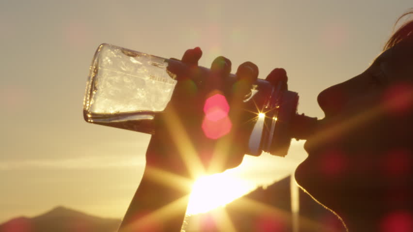 SLOW MOTION, CLOSE UP: Healthy young attractive sportswoman hydrating herself and drinking fresh cold water from BPA free plastic bottle after exhausting exercise in the city on magical sunny evening | Shutterstock HD Video #19965601