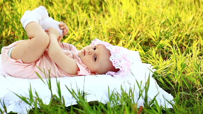 Baby lying on the grass and look at camera
