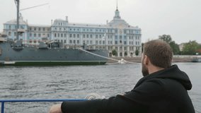 Sightseeing in St Petersburg. Handsome man explores, takes photos of the Cruiser Aurora, uses his smartphone, slow mo