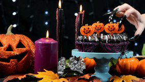 Halloween party table with spooky hand with long black nails stealing a chocolate cupcake.  - Powered by Shutterstock - Get 15% off with code: PIKWIZARD15