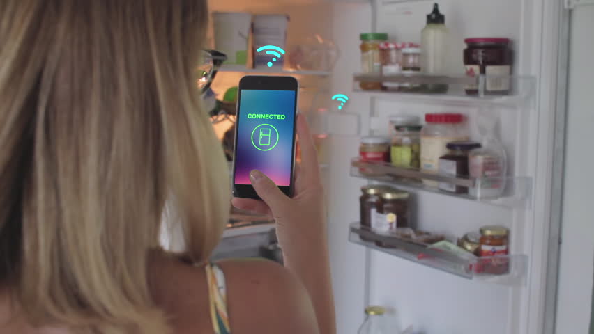Internet of Things - Young woman controls household connected devices & appliances with a smartphone - 29th September 2016