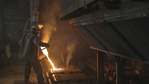Worker pouring red-hot steel in a steel mill