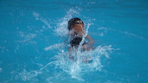 healthy boy front crawl swims slow motion in swimming pool , Asian young kid training with swim goggles high speed camera