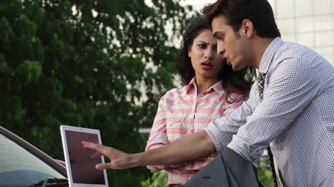 HD footage of young office going Indian man and woman working on lap top, tablet and talking.
