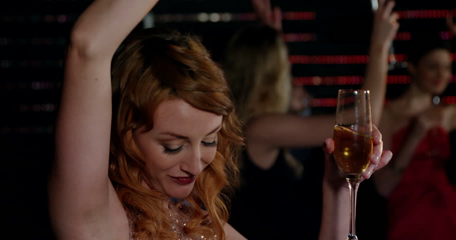 Beautiful woman dancing while having champagne in pub at bar 4k