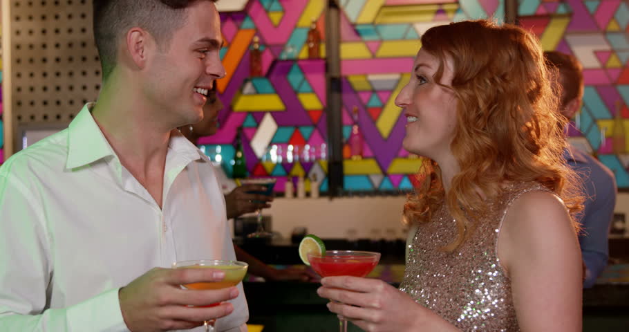 Couple interacting with each other while having cocktail in bar 4k