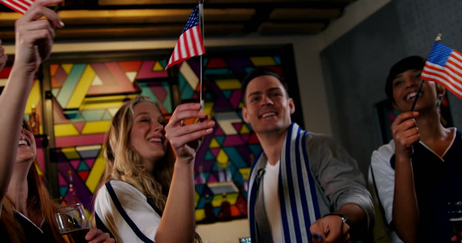 Group of friends waving american flag in bar 4k
