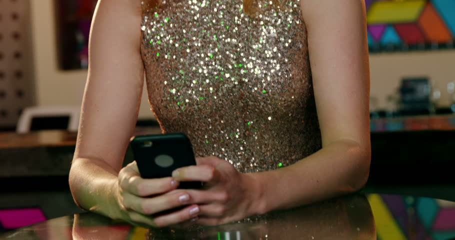Beautiful woman using mobile phone in bar 4k