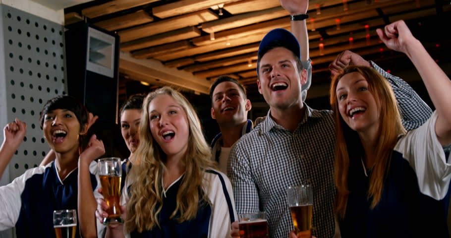 Group of friends cheering while watching tv in bar 4k