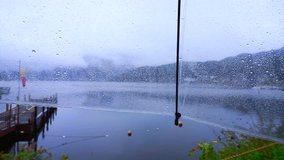 POV point of view sitting alone at lake on the rainy day. Clear umbrella and raindrops dripping. Abstract sad and lonely
