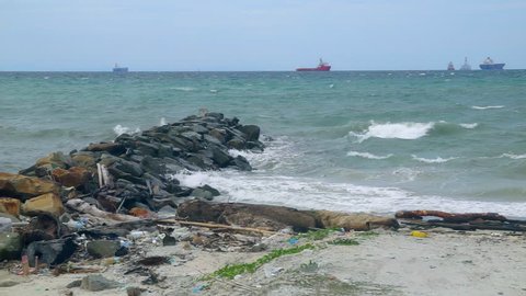 Ocean waves crashing over the stone embankment in Labuan beach,Malaysia. Big waves at open sea. Summer monsoon.