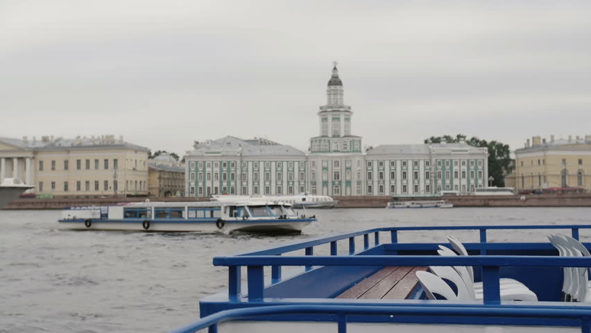 The river Neva quay, St Petersburg. A river bus floating on it, beautiful city architecture at the background.