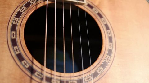 Dolly shot of close up view of acoustic guitar