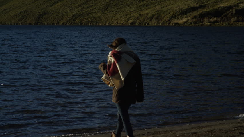 Camping woman walking down by the water on cold morning