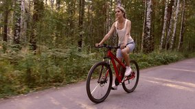Young fair-skinned woman rides a bike through the forest