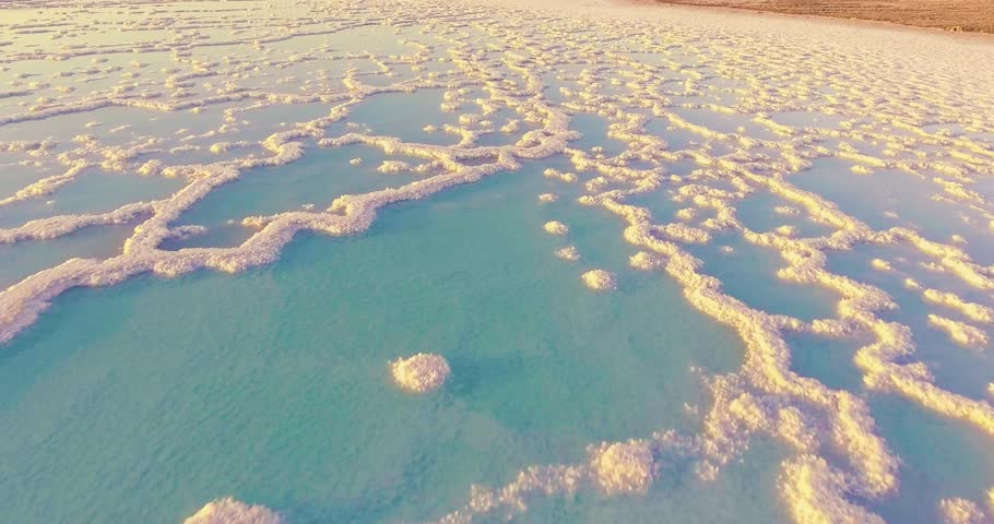 4K aerial video of the Dead Sea, shimmering salt water and healing mud, perfume breeze and sunlight reflections — a cinematic flight above nature’s miracle. 
