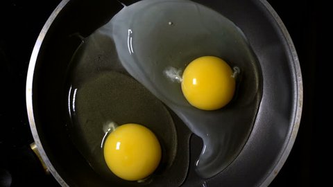 Two eggs fried in a pan. Time lapse. Top view.