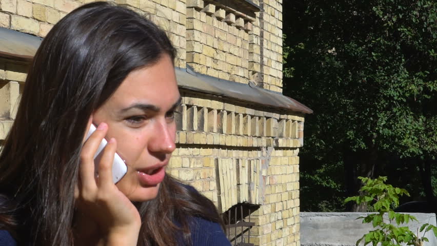 Young girl talking on the phone outside an ancient building