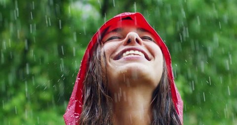 A happy woman smiles in the rain, the woman immersed in the nature of dance under the happy and free rain in slow motion. Concept of love, nature, happiness, freedom.