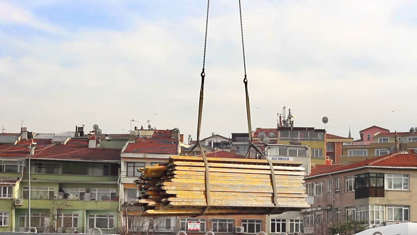 Crane lifting up heavy rods at the construction site
