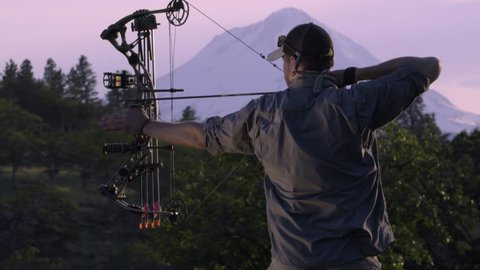 Elk Hunter Practices Using His Compound Bow At Sunset In The Mountains