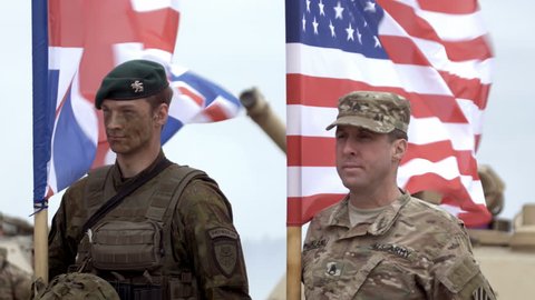 GAIZIUNAI, LITHUANIA - JUNE 18, 2015: Soldiers stand and hold flags. USA and UK flags during NATO exercise Saber Strike 2015.