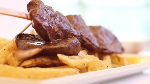 Appetizing hot heart beef peruvian dish called "anticucho" with fries. Selective focus. 