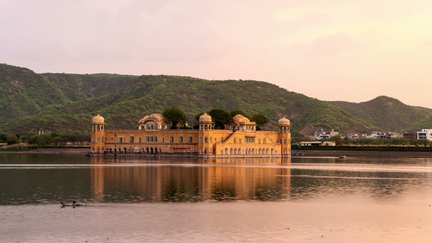 Jal Mahal palace at sunset in Jaipur, India. Popular landmark surrounded by water. Mountains at the background. Day to night time-lapse