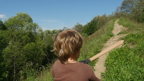 Back view of little boy with a wooden sword runs up the hill, Full HD steadicam shot