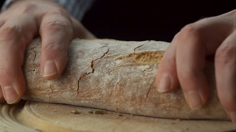 static view of mans hands tearing loaf of bread in half