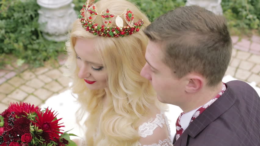 Young bride in the crown and groom in a jacket and tie are looking up and smiling. Happy faces of just married close up. Man and woman looking into the camera and smiling. Wedding day.