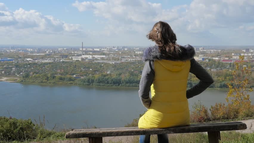 Girl sitting on a bench and looks at the panorama of the city