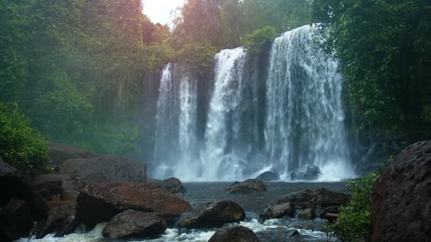 Wide curtain of whitewater flows continuously over the brink of a beautiful. natural waterfall in Cambodia. with sound.