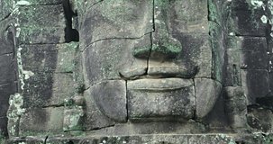 Closeup of an ancient. hand-carved. stone face. encrusted with lichen. at Bayon Temle. an important archaeological site in Cambodia.