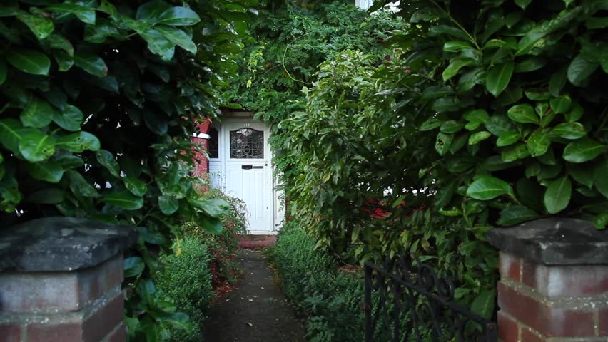 Girl in a yellow coat passes through the garden to the house, opened the door keys and comes into.