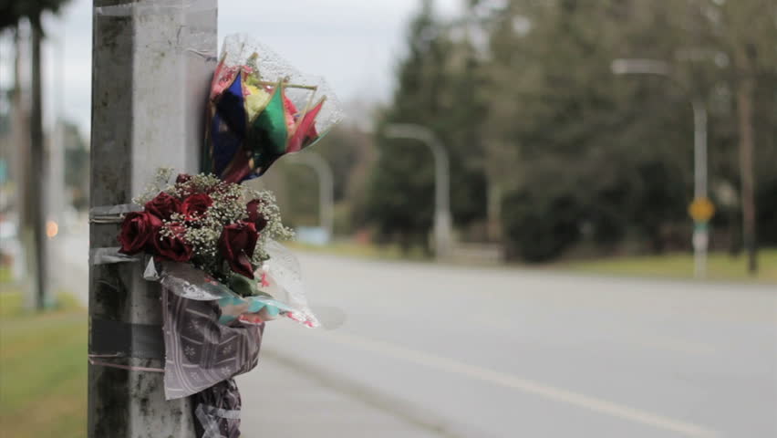 Flowers are taped against a light standard by the side of a busy street following a fatal auto accident serving as a reminder for all of us to "slow down" and drive safe!