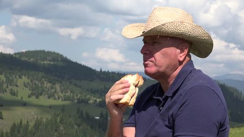 Farmer in a Mountain Farmland Taking a Break for Eating a Sandwich.