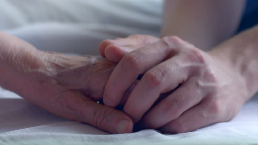 Tenderly comforting an elderly woman at the hospital. Close-up of a young man taking a hand of the sick senior. | Shutterstock HD Video #20129722