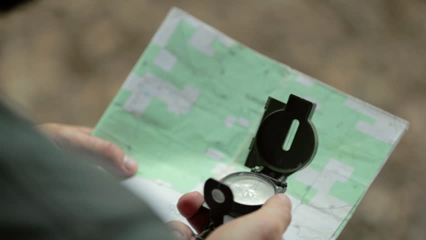 Over the shoulder of a man uses a magnetic navigational compass and map. Shallow focus. Royalty-Free Stock Footage #20131900