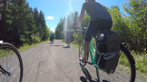 A smooth gimbal shot of a family riding their bikes through a beautiful pine tree forest in Cape Breton Nova Scotia Canada