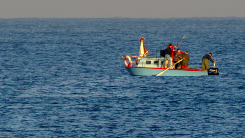 A surfer and fishing boat on the Mediterranean shot in Israel.