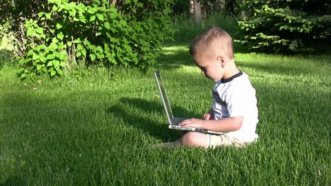 Boy sitting on the lawn playing on a laptop, then gets a confused look.