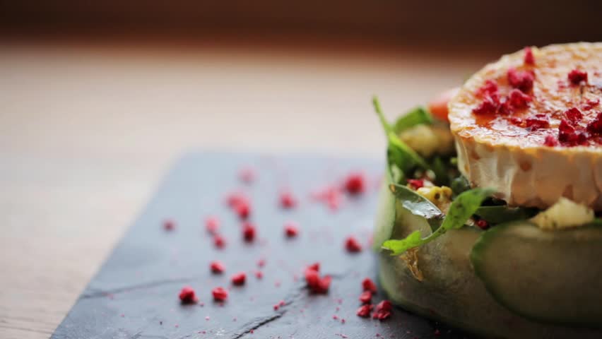 food, culinary, haute cuisine and cooking concept - goat cheese salad with vegetables and dried raspberries at restaurant or cafe