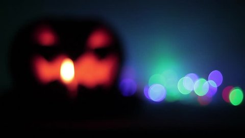 Defocused Closeup of scary holiday halloween carved glowing pumpkins. Flashing colored lights. Jack-O-Lantern