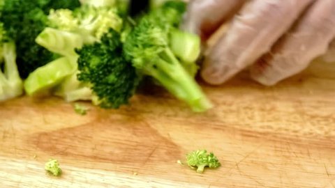 Fresh green broccoli being chopped into pieces, closeup