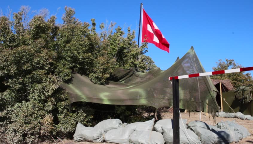Aid station, field hospital. Surgical care to the wounded in the war. Red cross flag in the wind on mobile medical camp