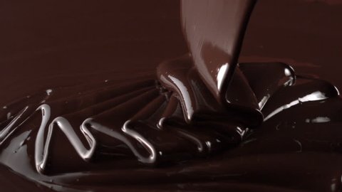 Rotation of chocolate pouring down with swirl in slow motion tabletop